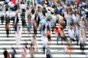 A blurred shot from above a crowd of pedestrians walking in a city crosswalk