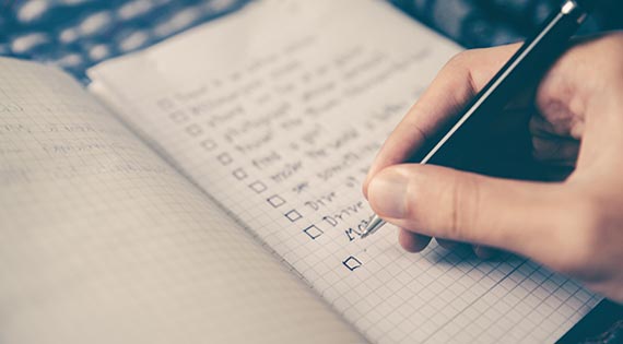 a journal with a hand writing a checklist inside