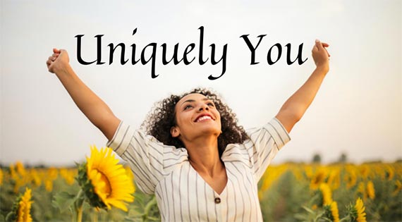 Picture of a woman out in a sunflower field looking up to the sky with her arms raised in victory. The picture has a title of Uniquely You