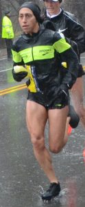 Desiree Linden running the 2018 Boston Marathon in a black and highlighter yellow outfit