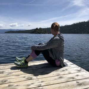 A woman sitting on a dock looking out at Lake Tahoe