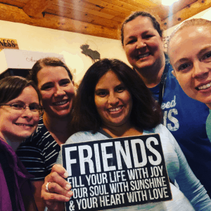 A group of college friends holding a sign that says "Friends fill your life with joy, your soul with sunshine, and your heart with love"