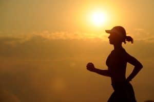 Silhouette of a woman running with the sun behind her