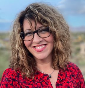 headshot of woman with brown wavy hair and glasses wearing a red and black blouse