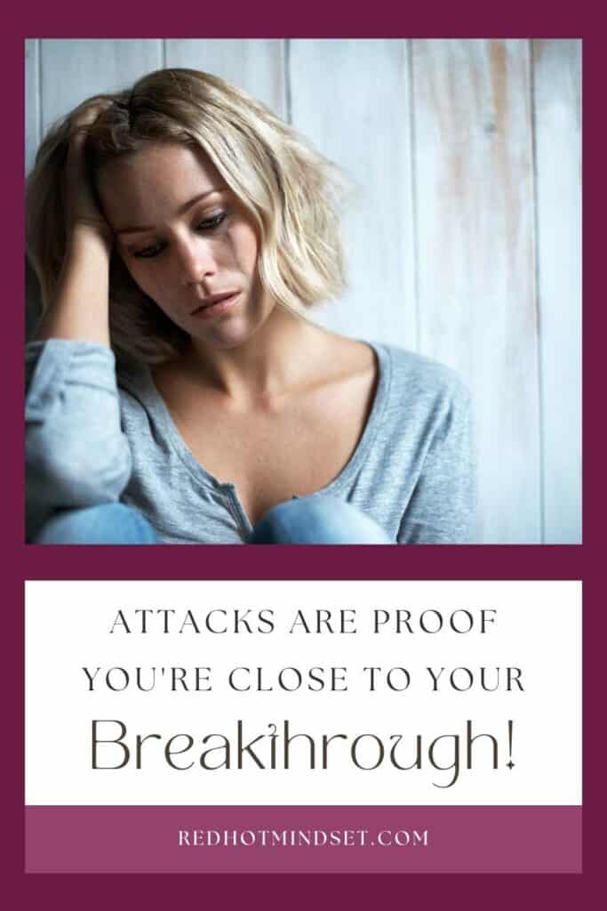 woman sitting with knees up leaning against a wall and leaning on one hand next to her head with title attacks are proof you're close to your breakthrough