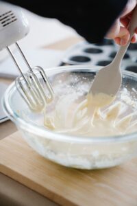 glass bowl with cookie batter, mixing with an electric mixer and spatula
