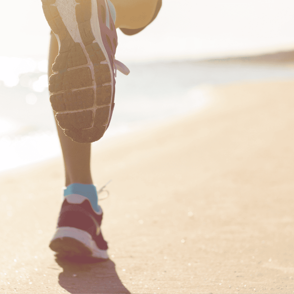 Legs of a runner running along the beach