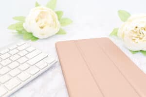rose gold journal with a white rose next to it and a little white keyboard