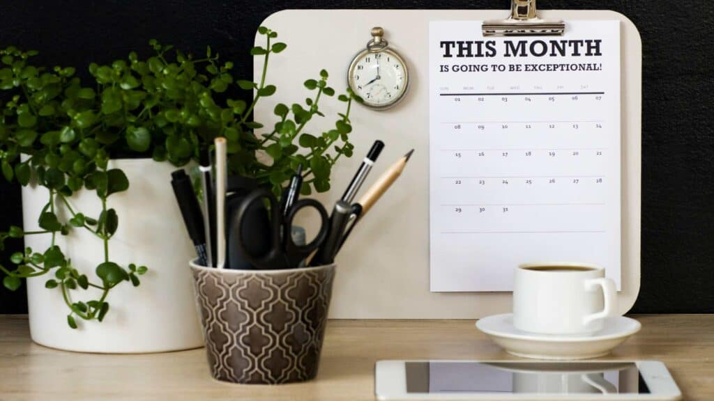 desk with a plant, writing utensils, and calendar