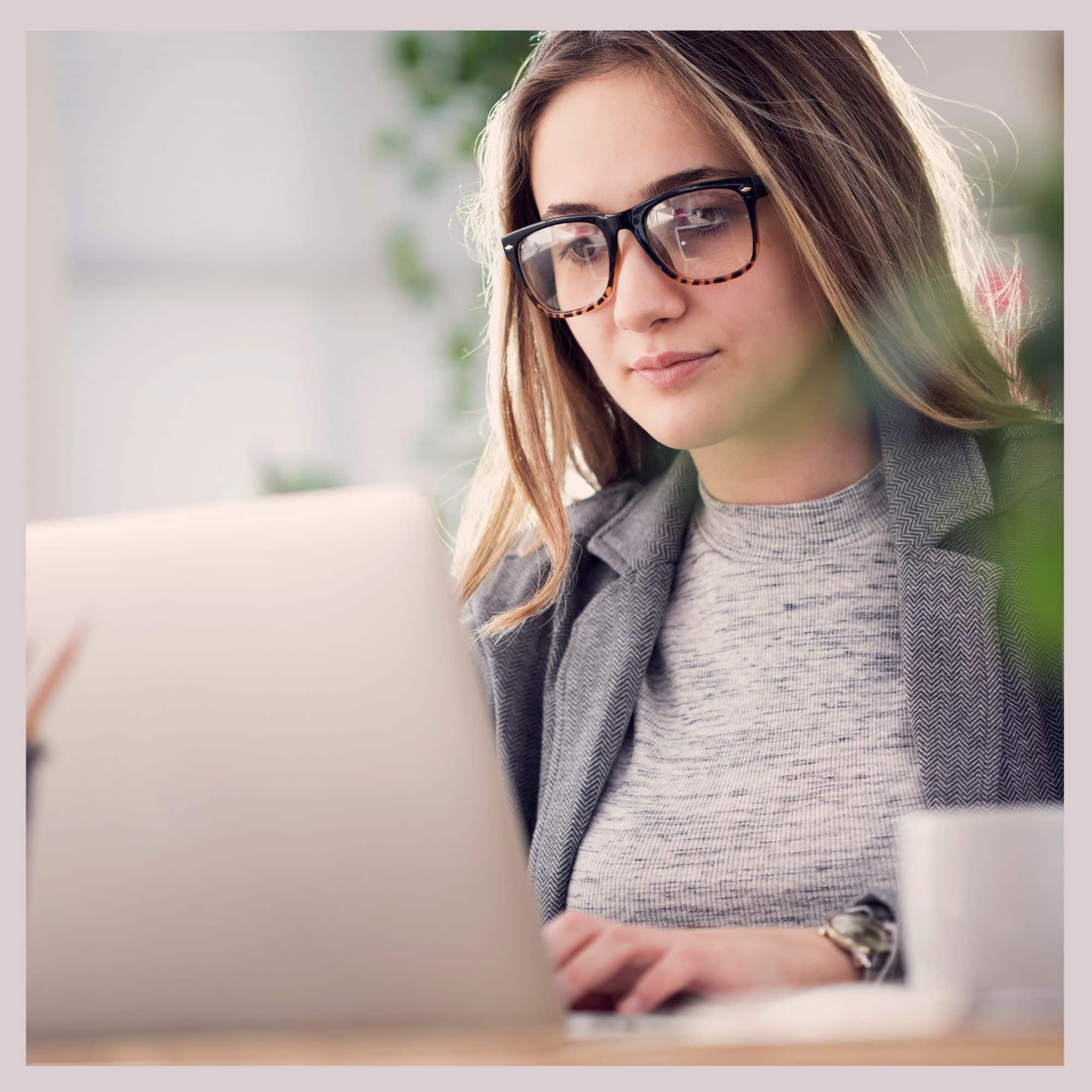 Woman with long blonde hair and glasses working at the computer